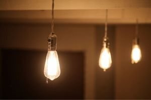 A row of three lightbulbs hanging from a ceiling, all lit.