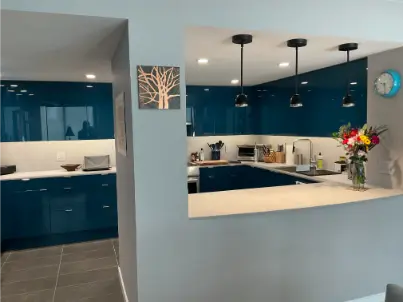 JDV Electric electrician standing on a ladder, installing a chandelier in homeowner's living room.